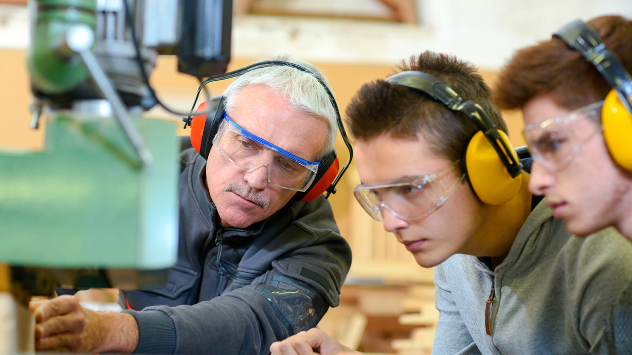A carpenter teaches two apprentices
