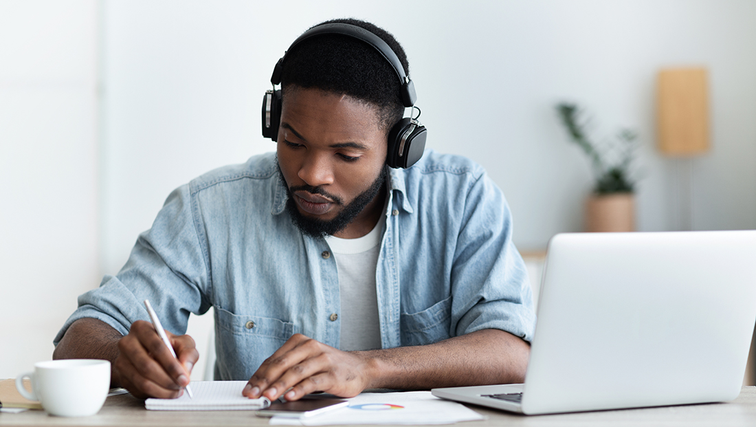 Racism in early careers: Black heritage student in headphones studying online