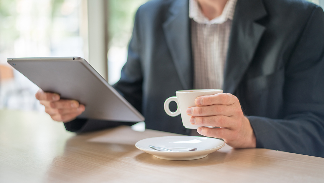 News digest: man holding a tablet, reading news and drinking coffee