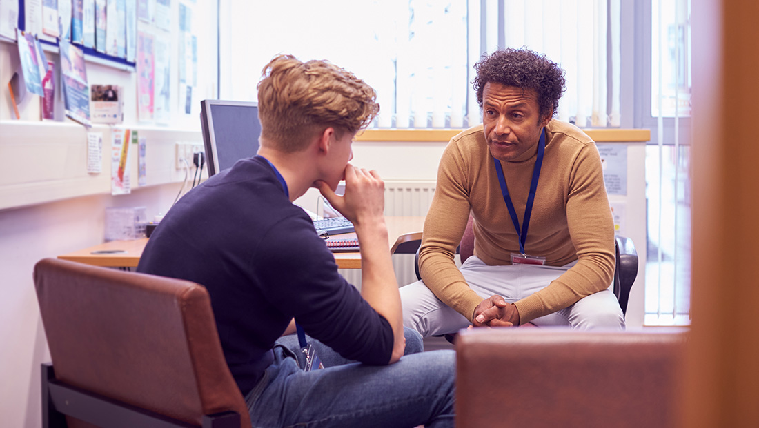 Student mental health: male university student meeting with campus counselor