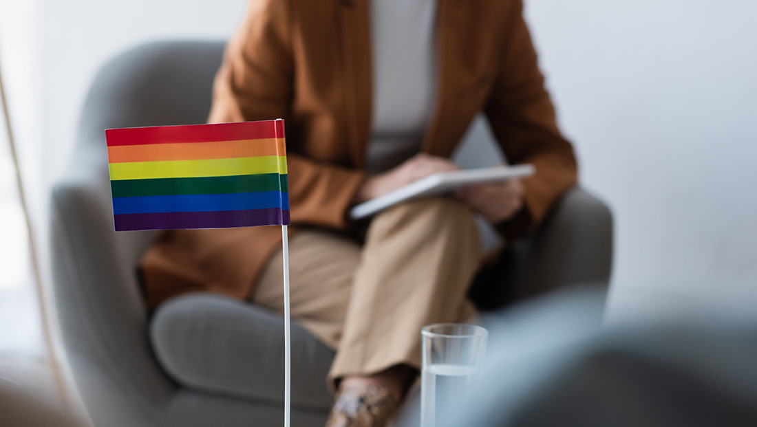 LGBTQ+ recruitment: An employee takign notes by a cofee table with a LGBTQ+ flag on top