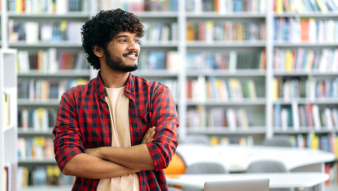 what students want: a student standing in a library with crossed arms