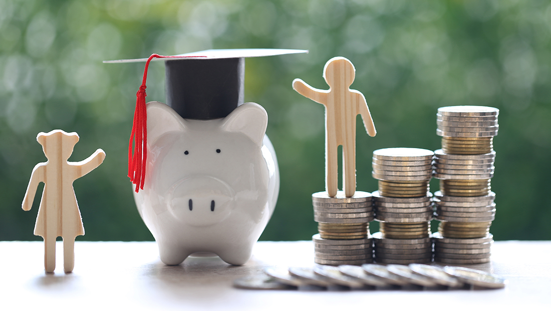 average graduate salary: graduation hat on piggy bank with stack of coins